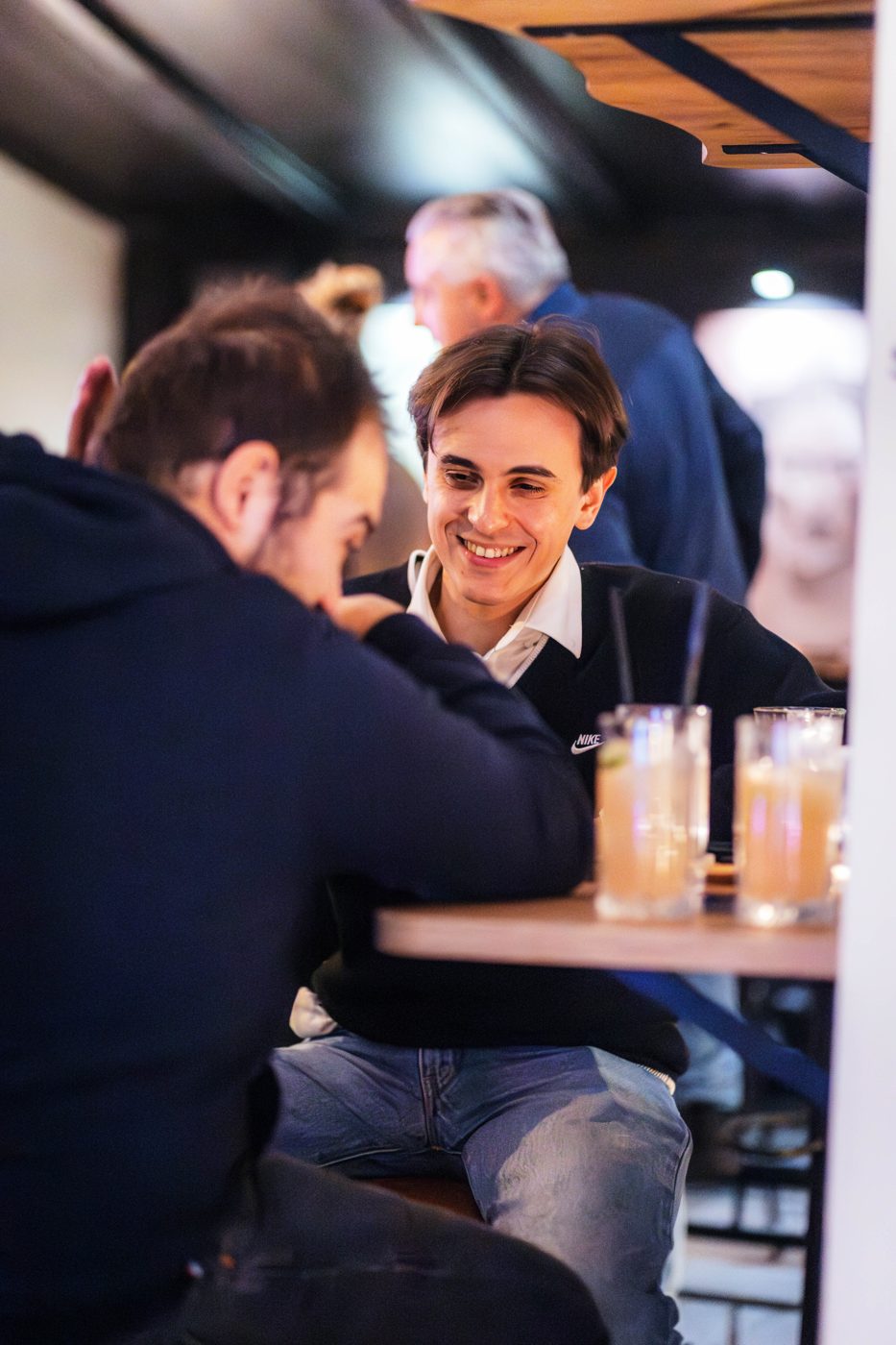Two friends smiling over drinks at RABOTEKA